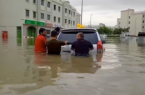 Thành phố sa mạc Dubai ngập lụt, 18 người chết ở Oman do mưa lớn- Ảnh 1. Người dân tại Dubai đẩy xe trong nước lụt ngày 16-4 - Ảnh: AFP/ ATIF BHATTI / ESN