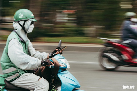 Một tài xế xe ôm công nghệ di chuyển với tốc độ cao. Tay phải vặn ga tay trái cầm điện thoại nhận đơn - Ảnh: THANH HIỆP Một tài xế xe ôm công nghệ di chuyển với tốc độ cao. Tay phải vặn ga, tay trái cầm điện thoại - Ảnh: THANH HIỆP