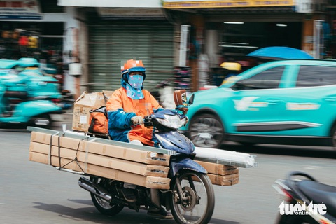 Một chị shipper chở các thanh sắt dài được cột ở 2 bên hông xe. Đầu các thanh sắt không được bịch lại gây nguy hiểm cho những người tham gia giao thông xung quanh - Ảnh: THANH HIỆP Một chị shipper chở các thanh sắt dài cột ở hai bên hông xe. Đầu các thanh sắt không được che chắn gây nguy hiểm cho những người tham gia giao thông xung quanh - Ảnh: THANH HIỆP