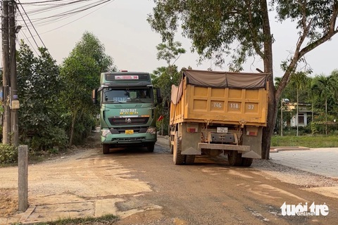 Đường làng thành đường công vụ, dân chặn xe thi công cao tốc vì gây bụi, mất an toàn- Ảnh 2. Hai xe tải lớn tránh nhau trên đường làng chật hẹp khiến người dân không thể đi lại - Ảnh: HOÀNG TÁO