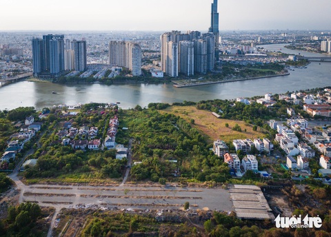 Hiện trạng dự án ‘nhà giàu’ kế khu đô thị Thủ Thiêm 23 năm chưa có đường vào- Ảnh 3. Nhìn về bên kia sông Sài Gòn và chung quanh công trình hiện đại sầm uất, còn dự án 1,8ha này cũng chỉ là bãi cây, cỏ um tùm. Bên cạnh là dự án Lê Quan cũng cỏ cây um tùm vì chưa được triển khai - Ảnh: ÁI NHÂN