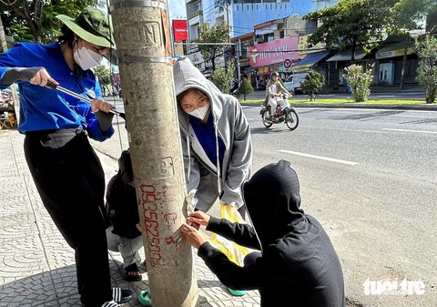 Đà Nẵng tính thưởng tiền cho người báo tin quảng cáo rao vặt sai quy định- Ảnh 2. Không chỉ dán giấy, nhiều người còn lăn số điện thoại bằng sơn lên các trụ điện - Ảnh: ĐOÀN NHẠN
