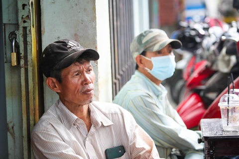 Cháy nhà ven kênh quận 8: Vẫn phong tỏa hiện trường, người dân chờ kiểm tra tài sản- Ảnh 4. Anh Trần Văn Lộc, công nhân xưởng gỗ, ngồi bần thần bên ngoài nơi bị cháy. Anh đã hỏi thăm, được biết xưởng gỗ anh làm việc không bị ảnh hưởng nhưng nhà của người quen vẫn chưa biết tình hình ra sao