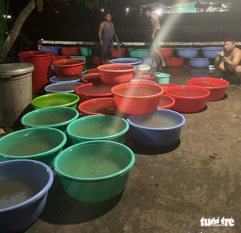 Nhiều phường xã ở Vĩnh Long bị cúp nước vì ông tài xế xe cuốc- Ảnh 2. Người dân khu vực chợ trung tâm thị xã Bình Minh, Vĩnh Long bơm nước sông lên chờ lắng cặn để xài - Ảnh: CHỊ LINH