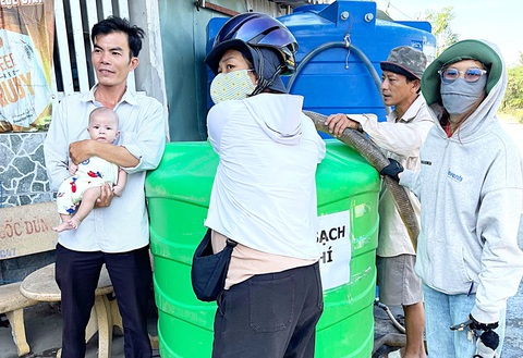 Bà bầu 8 tháng đưa nước về vùng khô khát- Ảnh 3. Chị Kim (đội mũ bảo hiểm) trực tiếp bơm nước vào bồn chứa giúp người dân - Ảnh: TRÚC QUYÊN