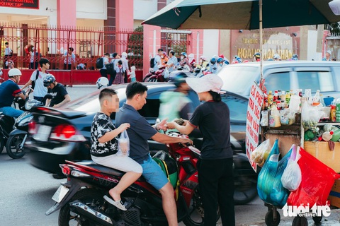 Phụ huynh dừng đậu xe giữa đường mua hàng rong cho con ảnh hưởng đến lưu thông xe cộ - Ảnh: THANH HIỆP Phụ huynh dừng đậu xe giữa đường mua hàng rong cho con - Ảnh: THANH HIỆP