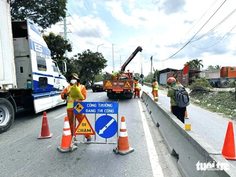 Lắp lại 19 đoạn dải phân cách bị mất trên đường Võ Chí Công- Ảnh 2. Sáng 23-4, công nhân và máy cẩu được huy động để lắp đặt lại các đoạn dải phân cách cứng bị mất dọc đường Võ Chí Công - Ảnh: THU DUNG