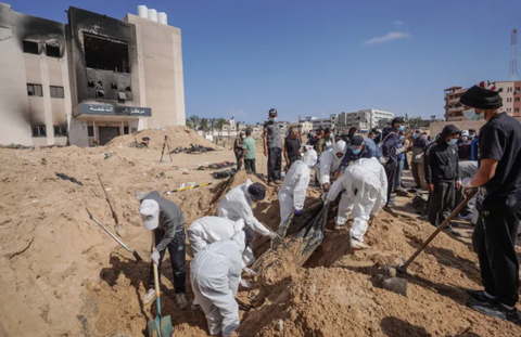 Phát hiện mộ tập thể gần 300 thi thể ở Dải Gaza, có dấu hiệu bị hành quyết- Ảnh 1. Các nhân viên y tế tại một mồ chôn tập thể nằm trong khuôn viên Khu liên hợp y tế Nasser, thành phố Khan Younis, Gaza ngày 21-4 - Ảnh: AFP