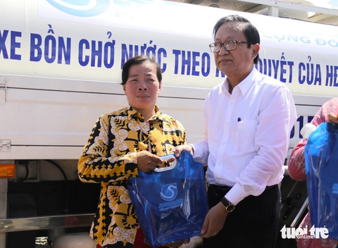 TP.HCM tặng nước ngọt hỗ trợ người dân bị ảnh hưởng bởi hạn mặn- Ảnh 1. Ông Nguyễn Thanh Sử - phó tổng giám đốc Sawaco - cùng các lãnh đạo địa phương trao tặng túi nước sạch cho người dân xã Phú Đông - Ảnh: TIẾN QUỐC