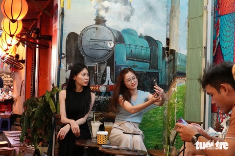 Hai du khách không đợi được tàu thì selfie với đoàn tàu trên bức tranh tường - Ảnh: T.T.D.