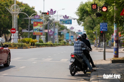 Quang cảnh đường phố Đông Hà trong nắng nóng kỷ lục 44 độ C- Ảnh 4. Số ít người dân ra đường nấp trong bóng cây khi dừng đèn đỏ - Ảnh: HOÀNG TÁO