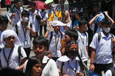 Philippines đóng tiếp cửa trường học, Lào xem xét cho học sinh nghỉ vì nắng nóng- Ảnh 5. Các học sinh cố gắng che chắn khỏi ánh nắng gay gắt tại Trường trung học President Corazon Aquino, thủ đô Manila - Ảnh: ABS-CBN