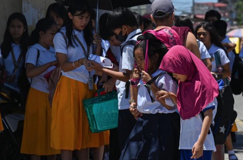 Philippines đóng tiếp cửa trường học, Lào xem xét cho học sinh nghỉ vì nắng nóng- Ảnh 1. Học sinh Philippines đi bộ dưới trời nắng gay gắt tại thủ đô Manila tháng 4-2024, trước khi có thông báo đóng cửa trường học - Ảnh: AFP