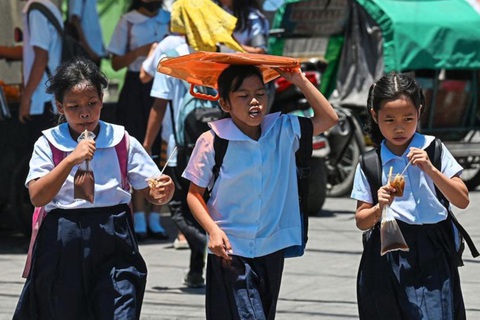Philippines đóng tiếp cửa trường học, Lào xem xét cho học sinh nghỉ vì nắng nóng- Ảnh 3. Một học sinh dùng túi che nắng sau giờ tan học tại thủ đô Manila tháng 4-2024 - Ảnh: AFP