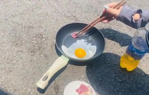 Trời nắng nóng, người Quảng Nam 'dí dỏm' mang chảo ra đường rán trứng- Ảnh 2. Ngoài rán trứng, người dân còn chiên thịt trên chảo - một cách đùa vui trước thời tiết nóng - Ảnh cắt từ clip