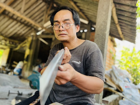 Thăm làng rèn đỏ lửa 300 năm được công nhận làng nghề OCOP 3 sao- Ảnh 1. Thợ rèn Lương Kim Hải kiểm tra độ sắc bén lưỡi dao mình làm ra - Ảnh: TRẦN MAI