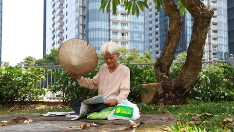 Trốn nóng dưới 'khách sạn' gầm cầu, bóng cây- Ảnh 6. Bà Phạm Thị Ngọc ra bờ kè kênh Nhiêu Lộc - Thị Nghè, đọc báo để tránh nóng