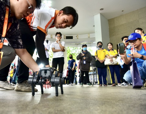 Các bạn trẻ chú ý đến robot chó của Trường ĐH Ngoại ngữ và Tin học - Ảnh: T.T.D. Chú robot chó của Trường ĐH Ngoại ngữ và Tin học thu hút sự chú ý của các bạn trẻ - Ảnh: T.T.D.