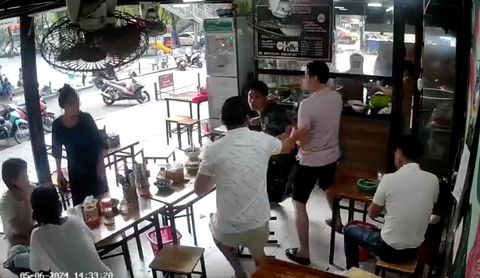 Xác minh vụ bỗng 'nhìn chằm chằm' rồi rút dao đâm trọng thương người cùng bàn ăn- Ảnh 1. Nghi phạm (áo đen) dùng dao tấn công người đàn ông mặc áo trắng - Ảnh cắt từ clip
