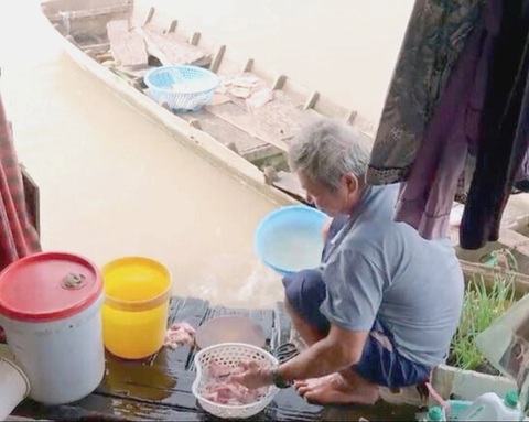 Ông Trần làm sạch đầu cá ba sa trước khi chế biến - Ảnh cắt từ màn hình Ông Trần làm sạch đầu cá ba sa trước khi chế biến - Ảnh cắt từ màn hình