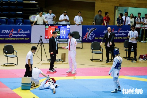 Hy hữu: Võ sĩ taekwondo Hàn Quốc bị xử thua khi đang dẫn 11-1- Ảnh 1. Trọng tài đang giải thích với HLV Hàn Quốc khi trận đấu tạm dừng để bác sĩ vào chăm sóc cho Hamdi Riad - Ảnh: N.K