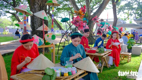 Về Đồng Tháp xem sen trên nón, trên quạt, trên tranh của lễ hội sen- Ảnh 2. Nhóm sinh viên Trường đại học Đồng Tháp tham gia vẽ tranh sen trên nón lá, tranh sen lên quạt tại công viên Văn Miếu - Ảnh: ĐẶNG TUYẾT