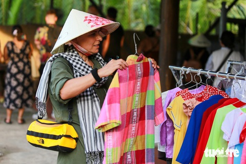 Ngồi tàu máy, đi xe điện khám phá cù lao ven sông Mekong- Ảnh 14. Bà Eva Alcalse (du khách người Tây Ban Nha) tìm hiểu sản phẩm du lịch của người dân tự thiết kế