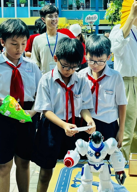 Học sinh hào hứng trải nghiệm làm 'công dân số'- Ảnh 2. Các em học sinh tiểu học chăm chú điều khiển robot tại ngày hội