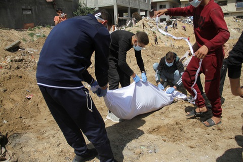 Nga kêu gọi quốc tế điều tra về các ngôi mộ tập thể ở Gaza- Ảnh 2. Người Palestine bên cạnh một thi thể được chôn trong ngôi mộ tập thể ở phía bắc Dải Gaza hôm 15-4 - Ảnh: REUTERS