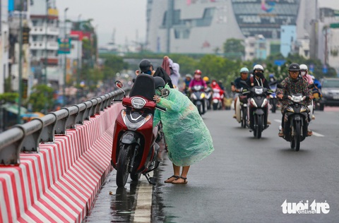 'Combo’ mưa và kẹt xe sáng đầu tuần ở TP.HCM: Thời tiết mát mẻ mà đi lại khó khăn- Ảnh 4. Mưa bất ngờ khiến một số người đi xe máy dừng mặc áo mưa ngay trên cầu vượt Bình Lợi - Ảnh: CHÂU TUẤN
