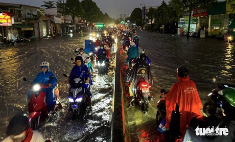 Đường lớn Phạm Văn Đồng ngập cả đoạn, hàng ngàn xe 'chết đứng'- Ảnh 2. Mưa kèm theo nước từ con rạch gần đó gây ngập đường Phạm Văn Đồng, một số người đi xe máy cố gắng chạy sát vào tim đường để đi - Ảnh: CHÂU TUẤN