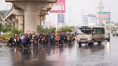 Trú mưa kiểu 'trời ơi đất hỡi'!- Ảnh 2. Người dân trú mưa lấn sát làn đường ô tô, cực kỳ nguy hiểm khi dòng xe đang xuống dốc cầu Sài Gòn - Ảnh: A.V