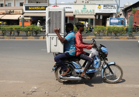 Giữa cái nắng hè gay gắt tại TP. Ahmedabad, bang Gujarat, Ấn Độ, hai người đàn ông chở nhau bằng xe máy để vận chuyển một chiếc máy làm mát không khí về nhà - Ảnh: REUTERS Giữa cái nắng hè gay gắt tại TP. Ahmedabad, bang Gujarat, Ấn Độ, hai người đàn ông chở nhau bằng xe máy để vận chuyển một chiếc máy làm mát không khí về nhà - Ảnh: REUTERS