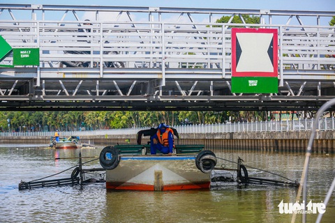 Ngược dòng Nhiêu Lộc - Thị Nghè tìm nguồn thải gây sự cố 100 tấn rác ùn ứ- Ảnh 3. Khi nước lên và qua những dạ cầu thấp, các nhân viên phái hạ thấp người xuống để tránh va vào cầu - Ảnh: Nhóm phóng viên