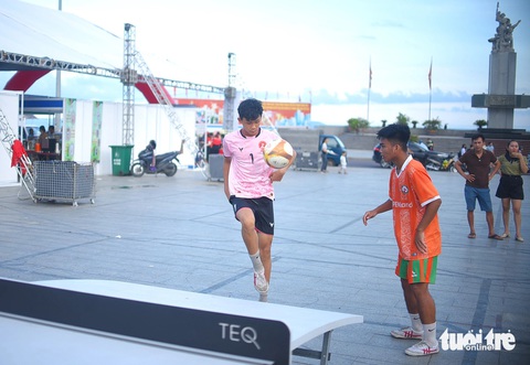 Quy Nhơn đặt nhiều bàn bóng đá trên bàn Teqball trên bãi biển, người dân thích thú- Ảnh 7. Một pha phối hợp giữa 2 bạn chơi - Ảnh: LÂM THIÊN