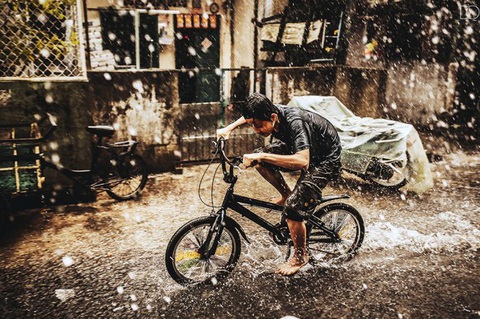 Những mùa mưa đợi chờ - Kỳ 4: Mưa Sài Gòn bao mùa thương nhớ- Ảnh 3. Cậu bé đạp xe trong màn mưa Sài Gòn - Ảnh: DOÃN QUANG