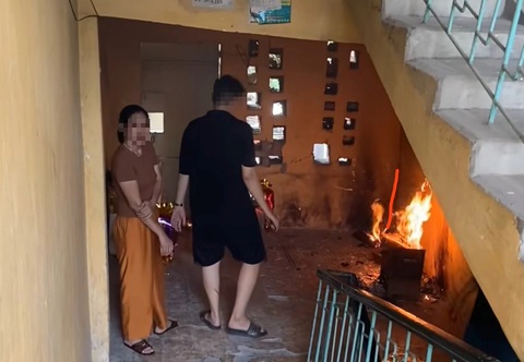 Bị nhắc vì đốt vàng mã ở cầu thang khu tập thể, người phụ nữ nói 'ở đây 40 năm chưa cháy bao giờ'- Ảnh 1. Hình ảnh bà H. cùng người nhà đốt vàng mã tại sảnh cầu thang nhà tập thể cũ tiềm ẩn nguy cơ cháy, nổ - Ảnh cắt từ clip