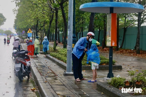 TP.HCM mưa dông nhiều nơi từ sáng sớm, sấm rền vang trời- Ảnh 4. Các em nhỏ được người lớn mặc vội áo mưa. Hình ảnh ghi nhận trên đường Mai Chí Thọ (TP Thủ Đức) - Ảnh: CHÂU TUẤN