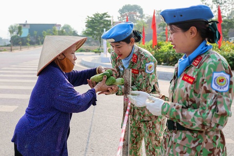 Những Bà Nguyễn Thị Tơ, một người dân địa phương, tặng dưa chuột cho các cô gái thuộc khối lực lượng Gìn giữ hòa bình, tất cả dưa chuột đều được bà Tơ tuyển chọn và ngâm nước muối sát trùng kỹ càng, nhằm đảm bảo sức khỏe cho các chiến sĩ - Ảnh: NGUYỄN KHÁNH
