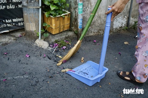 Cháy cỏ trong khu công nghệ cao, người dân khu vực Thủ Đức bức xúc khi tàn tro bay vào nhà- Ảnh 4. Người dân quét dọn liên tục nhưng không xuể - Ảnh: NGỌC QUÝ