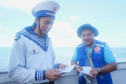 Vượt sóng đến Trường Sa, mang yêu thương nối liền đảo xa- Ảnh 1. Trung sĩ Đỗ Ngọc Lâm (trái) nâng niu cánh thư tay viết tay của học trò gửi ra đảo từ đất liền - Ảnh: HÀ THANH