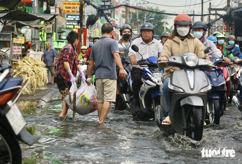Mưa mới 15 phút, rác từ rạch trồi lên đầy đường Tô Ngọc Vân, TP Thủ Đức- Ảnh 1. Người dân dọn rác từ con rạch trồi lên đường Tô Ngọc Vân (TP Thủ Đức) - Ảnh: CHÂU TUẤN