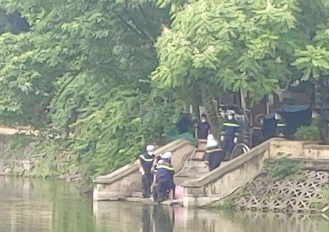 Thi thể nữ sinh viên đeo ba lô nổi trên mặt hồ ở Hà Nội- Ảnh 1. Cảnh sát đưa thi thể nữ sinh viên lên bờ - Ảnh: Người dân cung cấp