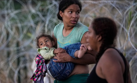 A woman carries her child after she and other migrants crossed the Rio Grande into the US. The image was part of a series by Associated Press photographers that won the 2024 Pulitzer prize for feature photography. Photograph: Eric Gay/AP Một người phụ nữ bế con sau khi cùng những người di cư khác vượt sông Rio Grande vào Mỹ. Bức ảnh nằm trong loạt ảnh giành giải Pulitzer năm 2024 hạng mục ảnh báo chí - Ảnh: Eric Gay/AP