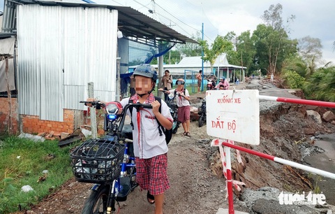 Mưa khiến vùng đệm U Minh Thượng sạt lở thêm: Địa phương có giải pháp gì?- Ảnh 3. Học sinh dắt xe đi bộ qua điểm sạt lở - Ảnh: CHÍ CÔNG