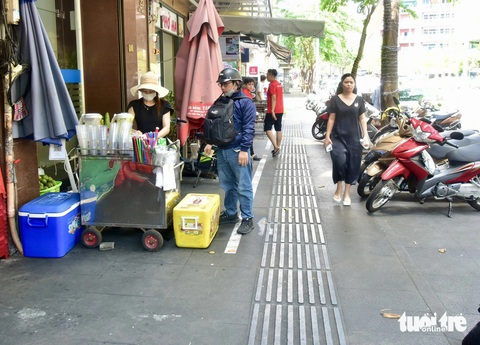 11 tuyến đường nào ở quận 1 thí điểm 'cho thuê' vỉa hè làm điểm kinh doanh?- Ảnh 4. Chị Lê Thị Khuyên (bên trái) chuẩn bị đăng ký sử dụng vỉa hè để bán nước giải khát trên đường Hải Triều, phường Bến Nghé, quận 1 - Ảnh: T.T.D.