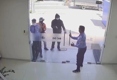 Vụ cướp ngân hàng 3,8 tỉ ở Hóc Môn: Nhóm cướp lên mạng tìm hiểu, mua vũ khí- Ảnh 2. Lợi và Mỹ cầm súng vào khống chế bảo vệ, uy hiếp nhân viên cướp tiền - Ảnh: Cắt từ video