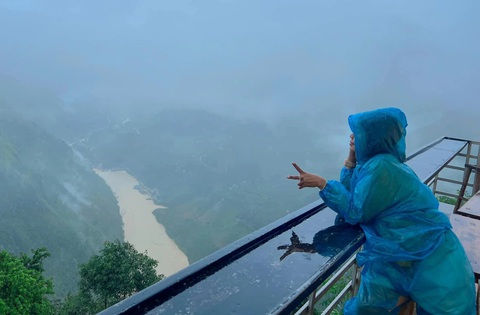 Đi Hà Giang 'chữa lành', du khách mắc kẹt do lũ- Ảnh 2. Hồng Thắm check-in với áo mưa, phía dưới là dòng Nho Quế mưa lũ cuồn cuộn - Ảnh: Nhân vật cung cấp