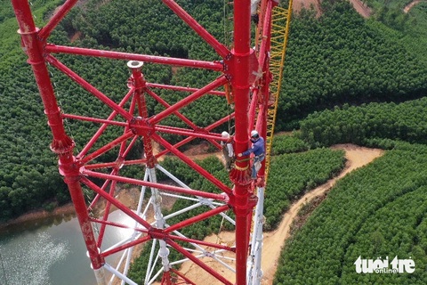 Thần tốc làm đường dây 500kV đưa điện ra Bắc - Kỳ 2: Đưa dòng điện vượt hồ Bộc Nguyên- Ảnh 2. Công nhân đu mình trên trụ cao chót vót giữa trời nắng nóng nhu đổ lửa, để nối từng thanh thép cột 175 Ảnh: B.D.