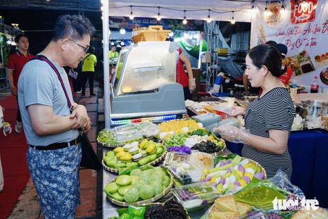 Du khách quốc tế thích thú đi 'chợ phiên không tiền mặt'- Ảnh 2. Ông Hishiro (du khách Nhật) đang chọn những loại bánh dân gian của Việt Nam để thưởng thức - Ảnh: THANH HIỆP